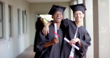 Mezuniyet şapkalı ve cüppeli iki melez çocuk geniş bir gülümseme sergiliyor. Lise başarılarını kutluyorlar. Okul koridorunda değişmeden, ağır çekimde duruyorlar.