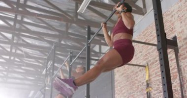 Spor salonunda egzersiz yapmak, sağlıklı bir kadının barfiks çekmesi, güç antrenmanına odaklanması. Spor, spor, egzersiz, dayanıklılık, kaslar, sağlık