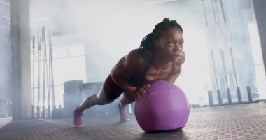 Spor salonunda egzersiz yapan, mor tıp topuyla şınav çeken bir kadın. Fitness, egzersiz, egzersiz, güç, eğitim, sağlık