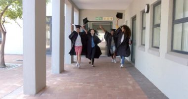 Çeşitli mezunlar bir lise koridorunda kutlama yapıyor. Birlikte önemli bir akademik dönüm noktası olan yavaş çekim havayı dolduruyor..