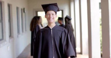 Gururlu genç çift ırklı çocuk lisede mezuniyetini kutluyor. Işıldayan gülümsemesi akademik başarının sevincini yansıtıyor ve önümüzde parlak bir gelecek var, ağır çekim..