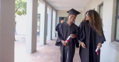 Çift ırklı mezunlar lise koridorlarında fotokopi çekerek yürürler. Akademik başarılarını kutlarken keyifli bir sohbeti paylaşıyorlar, ağır çekimde..