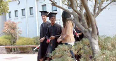 Mezunlar bir lise binasının önünde fotokopi çekerek kutluyorlar. Mezuniyet gününde çeşitli öğrenciler gururla ışıldıyor, ağır çekimde..