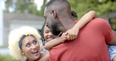 Afro-Amerikan ailesi evde havuz başında eğleniyor. Baba kızını kucaklıyor, anne gülüyor, oğul arkadan gözetliyor, giyinmiş, neşeli anları paylaşıyor, değişmemiş, yavaş çekim.