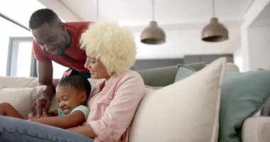 Çeşitli aileler evdeki kanepede birlikte vakit geçiriyorlar. Afro-Amerikalı bir adam melez bir kadına ve genç bir kıza tablet gösteriyor. Hepsi içten, değişmeden, ağır çekimde gülümsüyor.