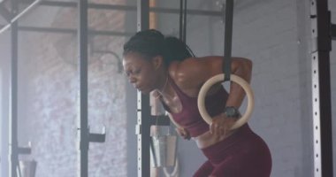 Jimnastik yüzüklerini kullanan güçlü formda bir kadın beden eğitimi ve fotokopi odasında egzersiz yapıyor. Fitness, jimnastik, egzersiz, atlet