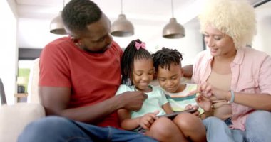 Çeşitli Afro-Amerikan aileleri birlikte oturup tablet izliyorlar. Baba kucağında bir cihaz, çocukları meşgul ediyor, anne yakından izliyor, rahat bir akşamın tadını çıkarıyor, değişmeden, ağır çekimde.