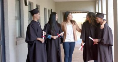 Çeşitli mezunlar başarılarını kutluyor. Gülümsemeler ve kahkahalar lise koridorunu dolduruyor..