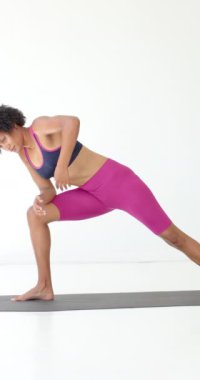 Dikey video: Yoga pratiği, stüdyoda yoga minderinde gerinen Afrikalı Amerikalı bir kadın. Spor, sağlık, egzersiz, esneklik, meditasyon, egzersiz, kapalı alan, ağır çekim