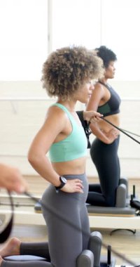 Dikey video: yoga pilates stüdyosunda direniş gruplarıyla egzersiz yapan Afrikalı Amerikalı kadınlar. Fitness, egzersiz, sağlık, yavaş çekim