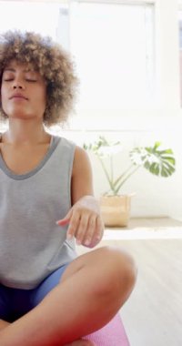 Dikey video: Yoga stüdyosunda meditasyon yapan, yoga minderinde bacak bacak üstüne atmış bir kadın. Meditasyon, farkındalık, rahatlama, zen, zindelik, sağlık