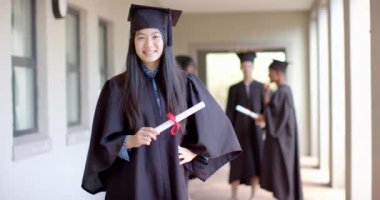 Mezuniyet kıyafetli Asyalı kız gururla, fotokopi odasıyla ışıldıyor. Onun başarısı lise ortamına neşe katıyor, yavaş çekimde..