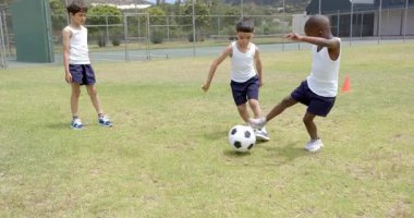 Futbol oynuyor, okul üniformalı üç çocuk sahada eğleniyor. Takım çalışması, çocuklar, spor, tekme, değiştirilmemiş, yavaş çekim