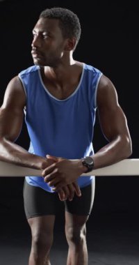 Dikey video: Spor giyim sektöründe güçlü ve formda bir sporcu bara yaslanmış, kararlı görünüyor. Fitness, strength, determination, work, motivasyon, slow motion