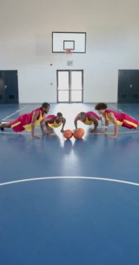 Dikey video: Basketbol oyuncuları antrenman sırasında sahada şınav çekiyorlar, fotokopi çekiyorlar. Spor, egzersiz, spor, takım çalışması, spor, spor.