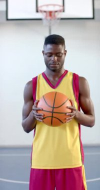 Dikey video: Basketbolu tutmak, maçtan önce spor forması giyen erkek oyuncu odaklanıyor. Sporcu, konsantrasyon, hazırlık, rekabetçi, takım, kararlılık