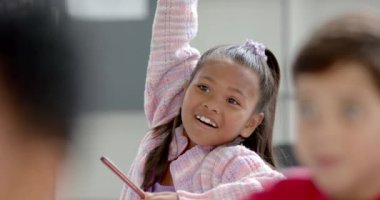 Okulda, uzun siyah saçlı melez genç bir kız sınıfta konuşuyor. Pembe bir kazak giyiyor, arkadaşlarıyla bir tartışmaya girmiş, beyaz arka planda, değişmemiş, ağır çekimde.