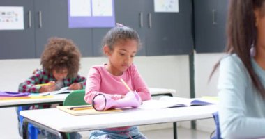 Okulda, sınıfın masasında not defterine yazan bir kız, işine konsantre oluyor. Eğitim, okula dönüş, öğrenme, öğrenme, çocukluk, öğrenci, değişmemiş, yavaş çekim