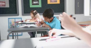 Çift ırklı erkek ve beyaz kız bir sınıftaki ödevlerine odaklanmış durumdalar. Güneş ışığı içeri akar, konsantrasyon ve öğrenme ortamını vurgular, yavaş çekim.