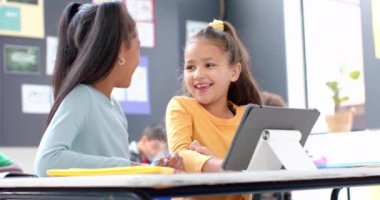 Okulda, sınıfta gülümseyen ve tablet kullanan iki kız vardı. Eğitim, teknoloji, öğrenme, öğrenme, çocukluk, arkadaşlar, değiştirilmemiş, yavaş çekim