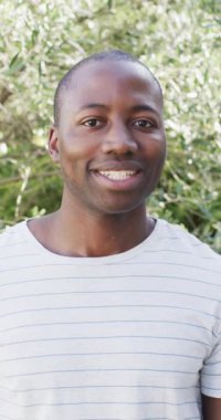 Dikey video: Karşılıklı kollar ve gülümseme, açık havada güneşli günün tadını çıkaran adam. Mutluluk, rahatlık, neşe, güneş ışığı, gündelik, yavaş çekim