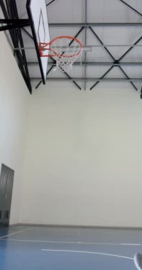 Dikey video: Basketbol oynamak, erkek sporcu spor salonunda basket atmak için atlıyor. skor, spor, eylem, dinamik, fitness, egzersiz