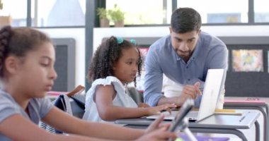 Genç Asyalı bir adam okulda dizüstü bilgisayarla ders veriyor. Melez bir kıza bilgisayar ödevinde yardım ediyor, ağır çekimde..