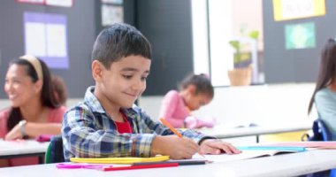 Okulda, not defterine kalemle yazı yazan bir çocuk, sınıf aktivitelerine odaklanıyor. Eğitim, öğrenme, öğrenme, çocukluk, ödev, okula dönüş, değişmemiş, yavaş çekim