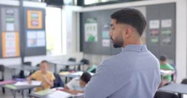 Okulda, fotokopi odası olan bir sınıfta genç bir Asyalı. Öğrencilerini ağır çekimde denetleyen bir öğretmene benziyor..