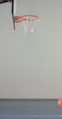 Dikey video: Smaç basketboluna atlamak, spor giyim sektöründe erkek sporcu potaya ulaşıyor. smaç, aksiyon, rekabet, atletik, smaç, yoğunluk