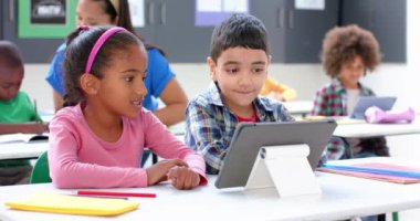 Okulda, çocuklar tablet kullanır ve sınıfta birlikte çalışırlar. Eğitim, öğrenme, teknoloji, dijital, takım çalışması, işbirliği, değiştirilmemiş, yavaş çekim