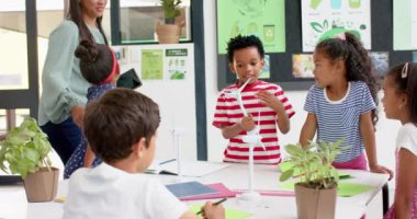 Okulda, öğretmen ve öğrenciler rüzgar türbinleriyle fen projesini tartışıyorlar. Eğitim, öğretim, sınıf, tartışma, rüzgar enerjisi, yenilenebilir, değiştirilmemiş, yavaş çekim