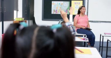 Okulda, öğretmen tableti tutarken öğrenciler cevap vermek için el kaldırıyordu. Eğitim, öğrenme, teknoloji, öğretim, bağlılık, etkileşim, değiştirilmemiş, yavaş çekim