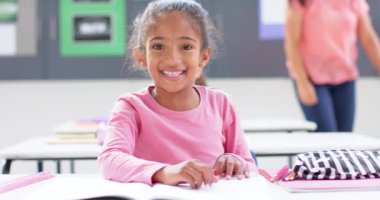 Sınıfta masada oturan gülümseyen kız açık bir not defteriyle. Eğitim, öğrenim, öğrenim, öğrenci, odaklanmış, akademik, değiştirilmemiş, yavaş çekim