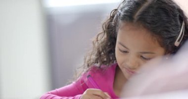 Okulda, sınıfta, melez bir genç kız yazmaya odaklanmış durumda. Kıvırcık kahverengi saçları var, pembe bir bluz giyiyor, işine odaklanmış, değişmemiş, ağır çekimde..