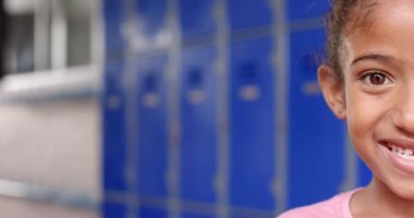 Koridordaki gülümseyen kız. Arka planda mavi dolaplar var. Kopya odası. Eğitim, öğrenci, okula dönüş, çocukluk, gülümseme, arkadaşlık, değişmemiş, yavaş çekim