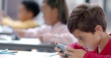 Okulda, çocuklar sınıfta tablet ve akıllı telefon kullanıyorlar, ekranlara odaklanıyorlar. Teknoloji, eğitim, dijital, öğrenme, öğrenciler, değiştirilmemiş, yavaş çekim