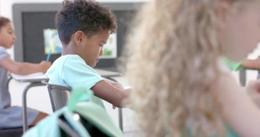 Çift ırklı çocuk okuldaki ödevlerine odaklanmıştı. Öğrenciler öğrenim faaliyetlerine girişiyor, eğitimin önemini vurguluyorlar, yavaş çekimde..