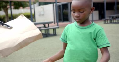 Okulda, çocuk karton tutuyordu ve oyun parkında kapkaççı aletleri kullanıyordu. açık hava, yaratıcılık, çocukluk, oyun, aktivite, eğlence, değiştirilmemiş, yavaş çekim