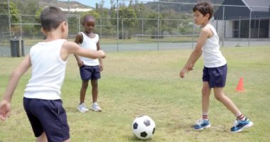 Okulda, beden eğitimi dersinde sahada futbol oynayan üç çocuk. Spor, takım çalışması, egzersiz, gençlik, açık hava, aktif, değişmemiş, yavaş çekim