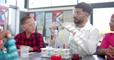 Bir okul sınıfında, melez bir öğretmen bir kimya deneyi yapar. Etrafı hevesli genç öğrencilerle çevrili, bir test tüpü tutuyor, meraklarını gideriyor, değişmemiş.