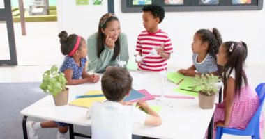 Okulda, öğretmenler masanın etrafında öğrencilerle takılıyor, projeyi tartışıyorlar. Eğitim, okula dönüş, öğrenme, öğretim, takım çalışması, işbirliği, değiştirilmemiş, yavaş çekim