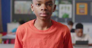 Sınıfta gülümseyen çocuk, arka planda sınıf arkadaşlarıyla okul aktivitelerinden zevk alıyor. Eğitim, okula dönüş, öğrenme, çocukluk, arkadaşlık, eğlence