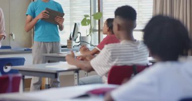 Proje sunumu, elinde tablet olan öğrenci ve okulda sınıf arkadaşlarıyla konuşma. Eğitim, sunum, teknoloji, sınıf, öğrenim, öğrenciler