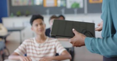 Okulda, çocuk sınıfta el kaldırıyor, öğretmenle yakınlaşıyor. Eğitim, öğrenim, öğrenci, etkileşim, akademik, soruşturma