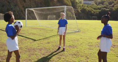 Okul sahasında futbol oynayan, kale direğinin yanında pas atan kızlar. Spor, takım çalışması, eğlence, spor, gençlik, açık hava