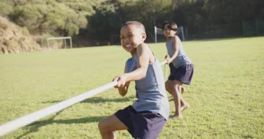 Halat çekme oyunu oynuyorlar, çocuklar arkadaşlarıyla okul sahasında eğleniyorlar. Çocuklar, eğlence, takım çalışması, spor, ara, egzersiz