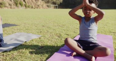 Yoga yapıyor, çocuklar dışarıda minderlere oturuyor, meditasyona odaklanıyor. Rahatlama, egzersiz, farkındalık, sükunet, zindelik