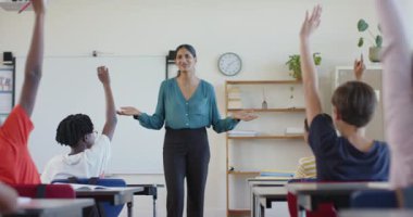 Okulda, sınıftaki sıralarda oturan öğrencilerle ilgilenen bir öğretmen. Eğitim, öğretim, öğrenme, müdahale, etkileşim