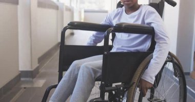 Okulun koridorunda tekerlekli sandalyede gülümseyen Afrikalı Amerikalı kız, gününün tadını çıkarıyor. eğitim, mutluluk, kapsama, çocukluk, erişilebilirlik, çeşitlilik